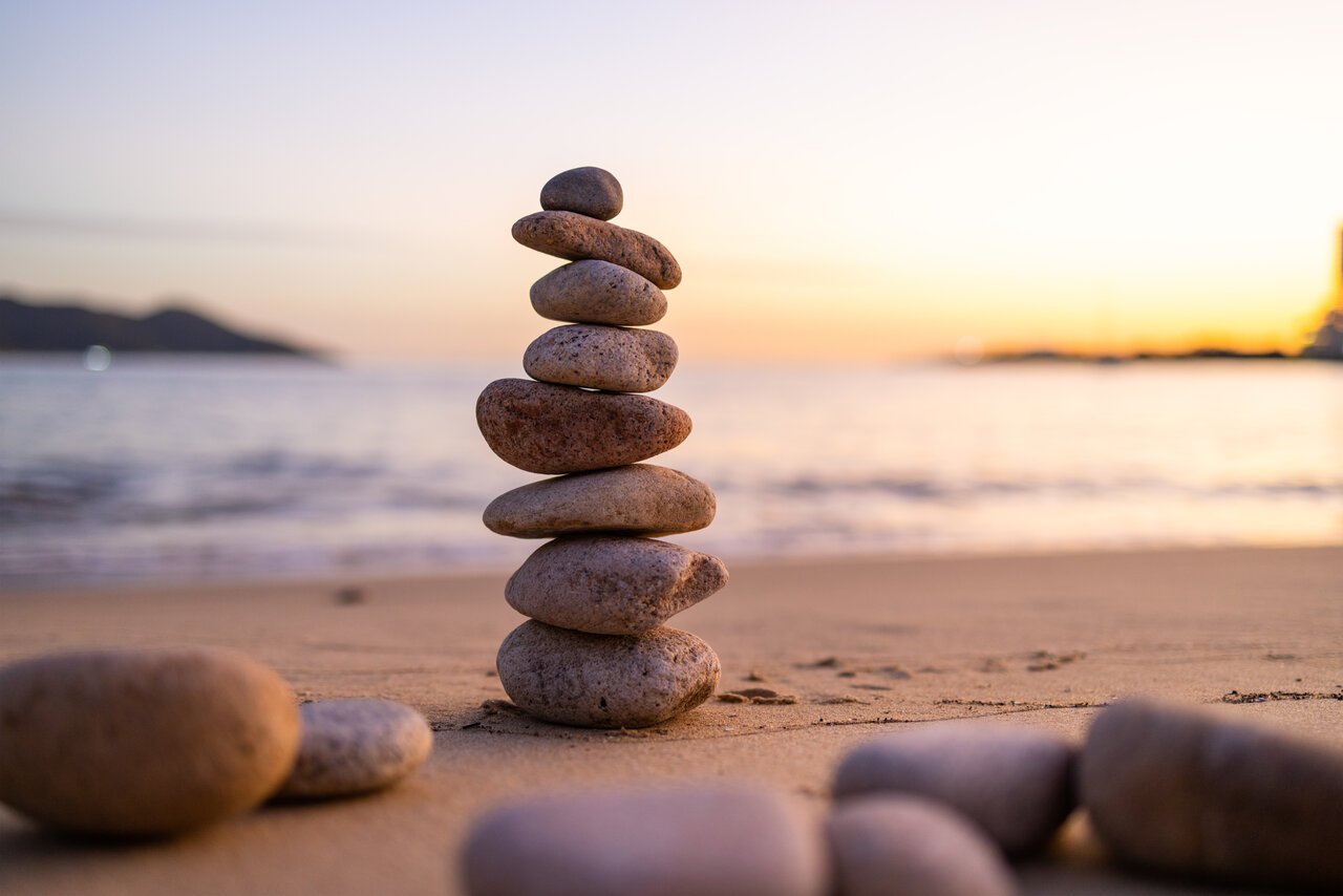 Balance pebble stone in the sand beach at sunset Balance pebble stone in the sand beach at sunset